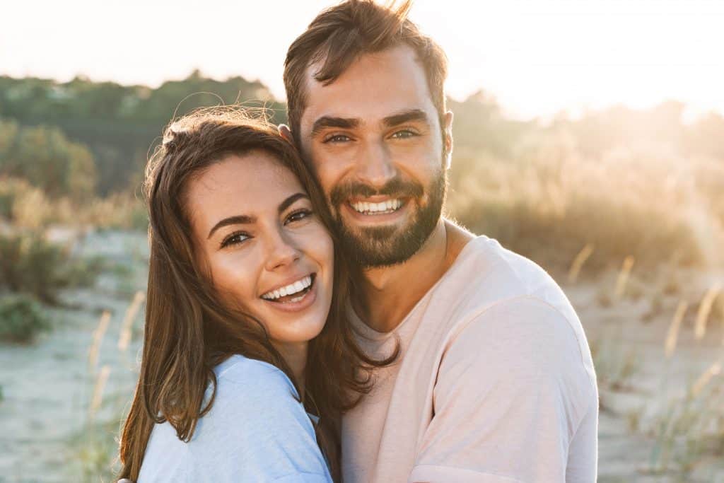 A couple smiling in the garden discussing how to deal with money issues in the relationship